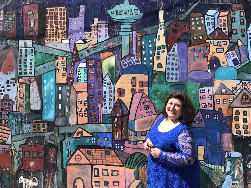 Laura Lozza In front of a colorful painted wall with many different buildings - mental safety