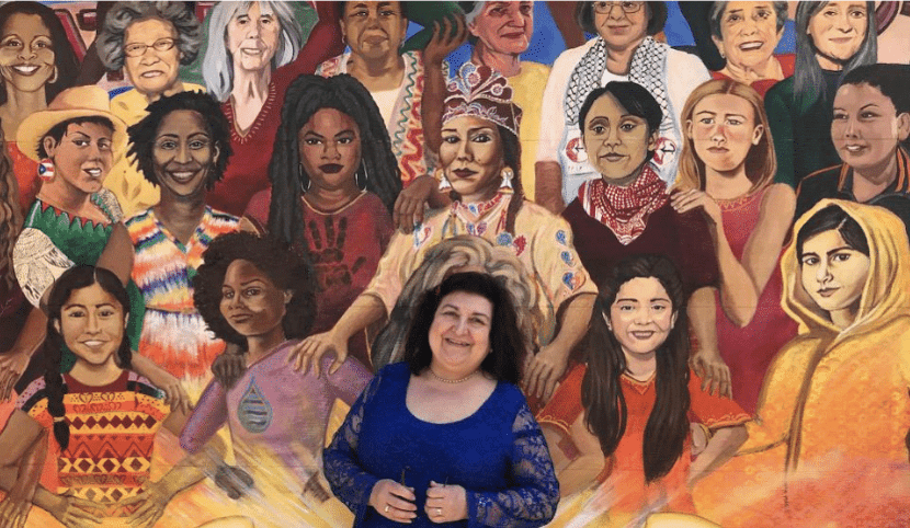 Laura Lozza in front of a painting with diverse women - LIS Woman is a Learning and Networking Membership for International Businesswomen